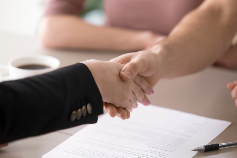 Man and woman handshaking after signing documents, successful de